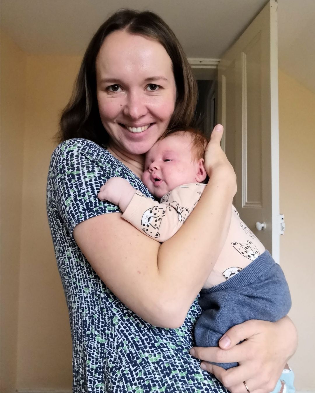 A mother holding her newborn baby, smiling happily.